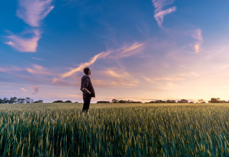 Ein Mann steht beim Sonnenuntergang in einem Getreidefeld